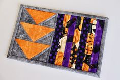 an orange and purple patchwork piece on top of a white surface with black dots