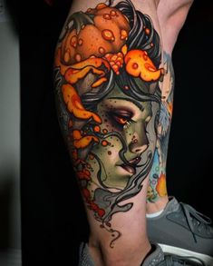 a woman's leg with an orange and black tattoo design on her thigh,