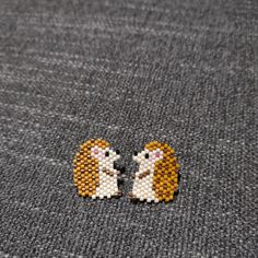 two small beaded animals sitting next to each other on top of a gray surface