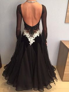 the back of a woman's black dress with white flowers and pearls on it