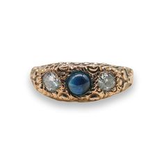 an antique gold ring with blue and white stones on the sides, set against a white background