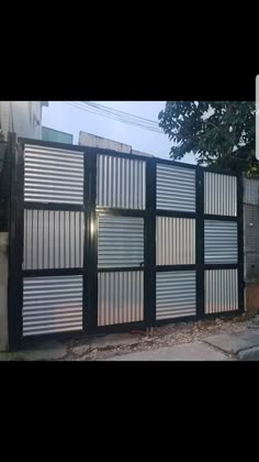 a black and white fence with metal slats on it's sides in front of a house