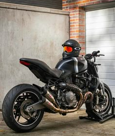 a motorcycle parked in front of a garage door with a helmet on it's head