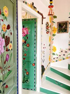 a green door with flowers painted on it and some stairs leading up to the second floor