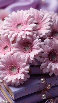 a bunch of pink flowers sitting on top of some purple books with pearls around them