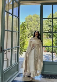 a woman standing in front of an open door wearing a white and gold outfit with sequins on it