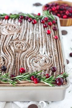 a cake with cranberries and rosemary sprigs is on a baking sheet