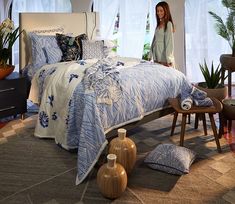 a bed with blue and white comforter in a bedroom next to two vases