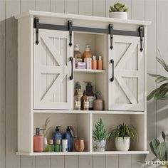 a white shelf with some bottles and plants on it next to a potted plant