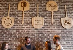 three people sitting at a table in front of some wooden paddles on the wall