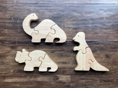 three wooden dinosaurs are shown on a wood floor