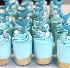 there are many small cupcakes with blue frosting and little mermaid decorations on them