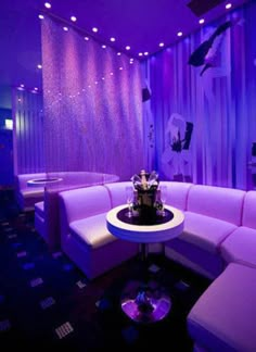 the room is lit up with purple lighting and furniture, as well as bottles of champagne