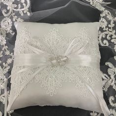 a white pillow on top of a black and white lace covered bed sheet with a bow