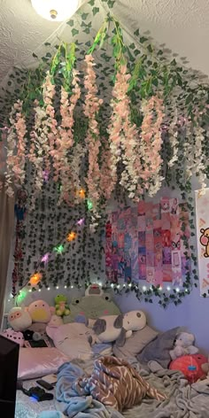 a bedroom with flowers hanging from the ceiling and stuffed animals on the bed in front of it