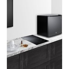 a black stove top sitting on top of a counter next to a wall mounted tv