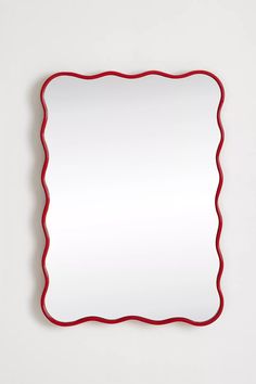 a square mirror with red trim around the edges on a white wall above it is an empty space for text