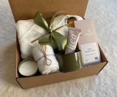 an open box with candles, towels and other items in it on a white carpet