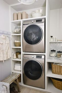 a washer and dryer in a small room with white shelves on the wall