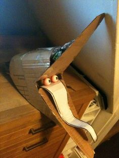 a pair of shoes with googly eyes in a cardboard box on top of a wooden floor