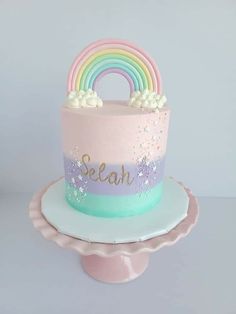 a pink and blue cake with a rainbow decoration on the top that says seah