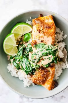 a white bowl filled with rice and chicken next to a slice of lime on top of it