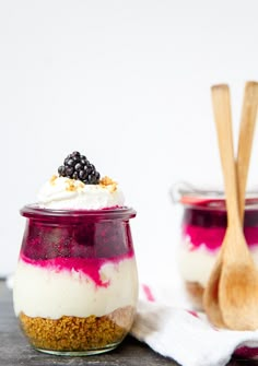 two jars filled with food sitting on top of a table next to a wooden spoon