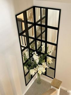 a vase filled with white flowers sitting on top of a wooden bench next to a mirror