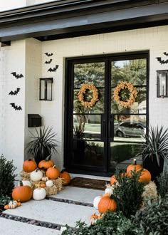 pumpkins and hay bales on the front steps of a white house with black doors