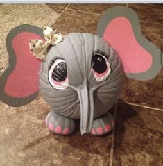 an elephant with a bow on it's head sitting on the ground next to a tile floor