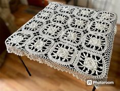 the table is covered with white crocheted doily and sits on a wooden floor