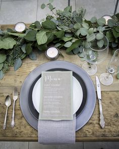 a place setting with silverware and greenery