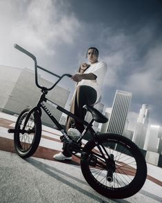 a man sitting on top of a bike in front of a cityscape with tall buildings