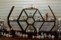 an assortment of cupcakes are displayed on a shelf in front of a wall