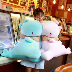 a woman holding two large stuffed animals in her arms while standing next to a counter