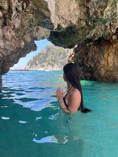 a woman is in the water near some rocks