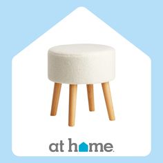 a white stool with wooden legs in front of a blue background and the words at home above it