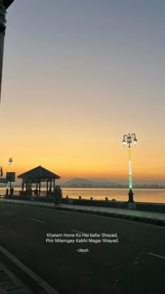 an empty street next to the water with a gazebo in the distance and a quote written on it