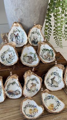 twelve porcelain dishes with animals on them are sitting on a wooden table next to a potted plant