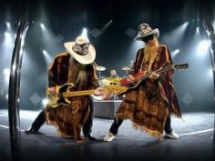 two men in costumes playing guitars on stage