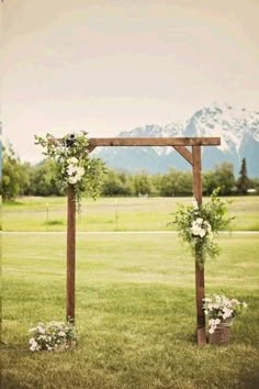 an outdoor ceremony setup with flowers and greenery on the grass in front of mountains