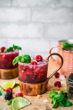 two glasses filled with raspberry mojitas on top of a wooden table