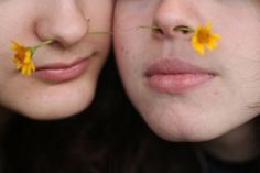 two women with flowers in their mouths