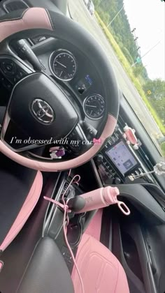 the interior of a car with pink trim and steering wheel controls, including an mp3 player