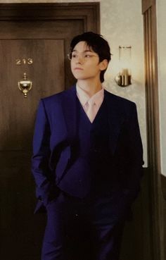 a man in a blue suit standing next to a door