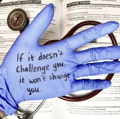 a hand wearing blue gloves with writing on it next to an open book that says if it doesn't challenge you, it won't change you