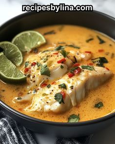 a close up of a bowl of soup with fish and limes on the side