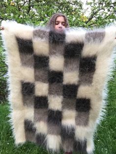 a man is holding up a checkered blanket in the grass with his face peeking out