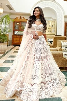 a woman in a white and gold bridal gown posing for the camera with her hands on her hips