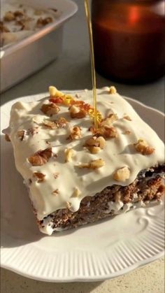 a piece of cake is being drizzled with icing and nuts on a plate